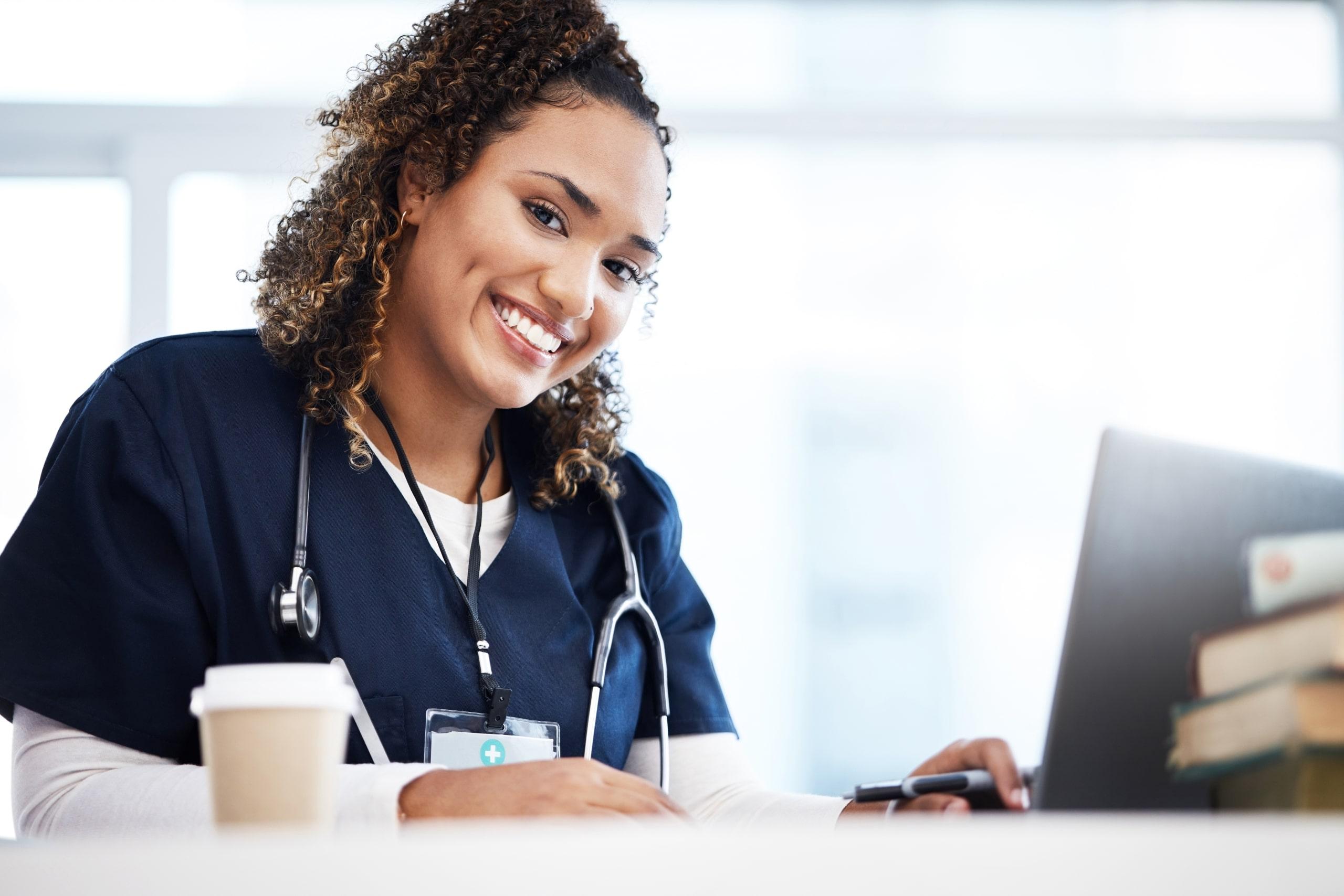 Smiling African-American nurse typing on a laptop